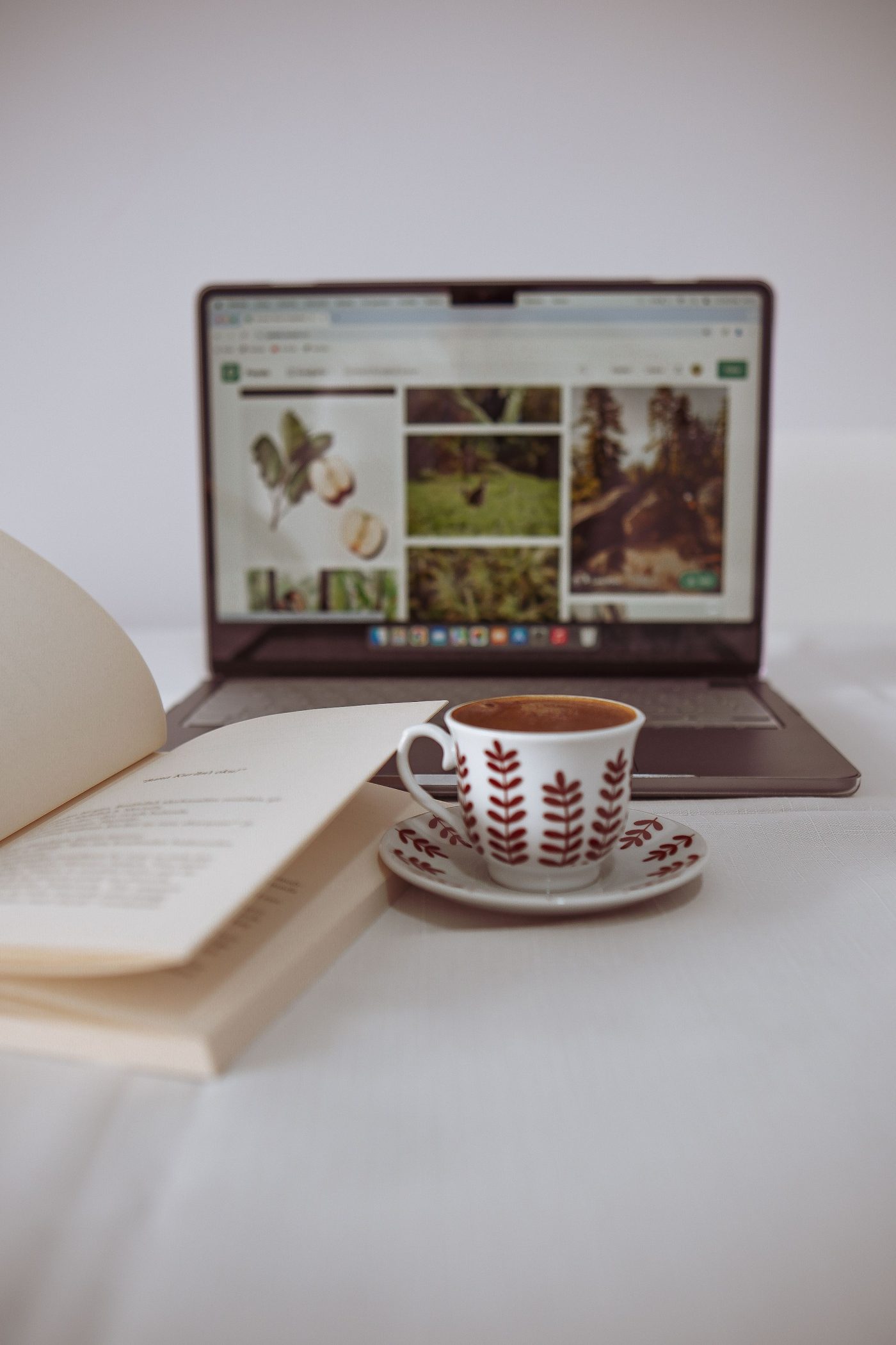 Open book and coffee beside a laptop on a minimal desk